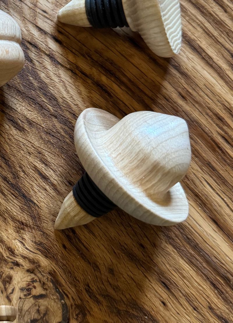 Wooden bottle stopper with black rubber gasket on a wooden surface