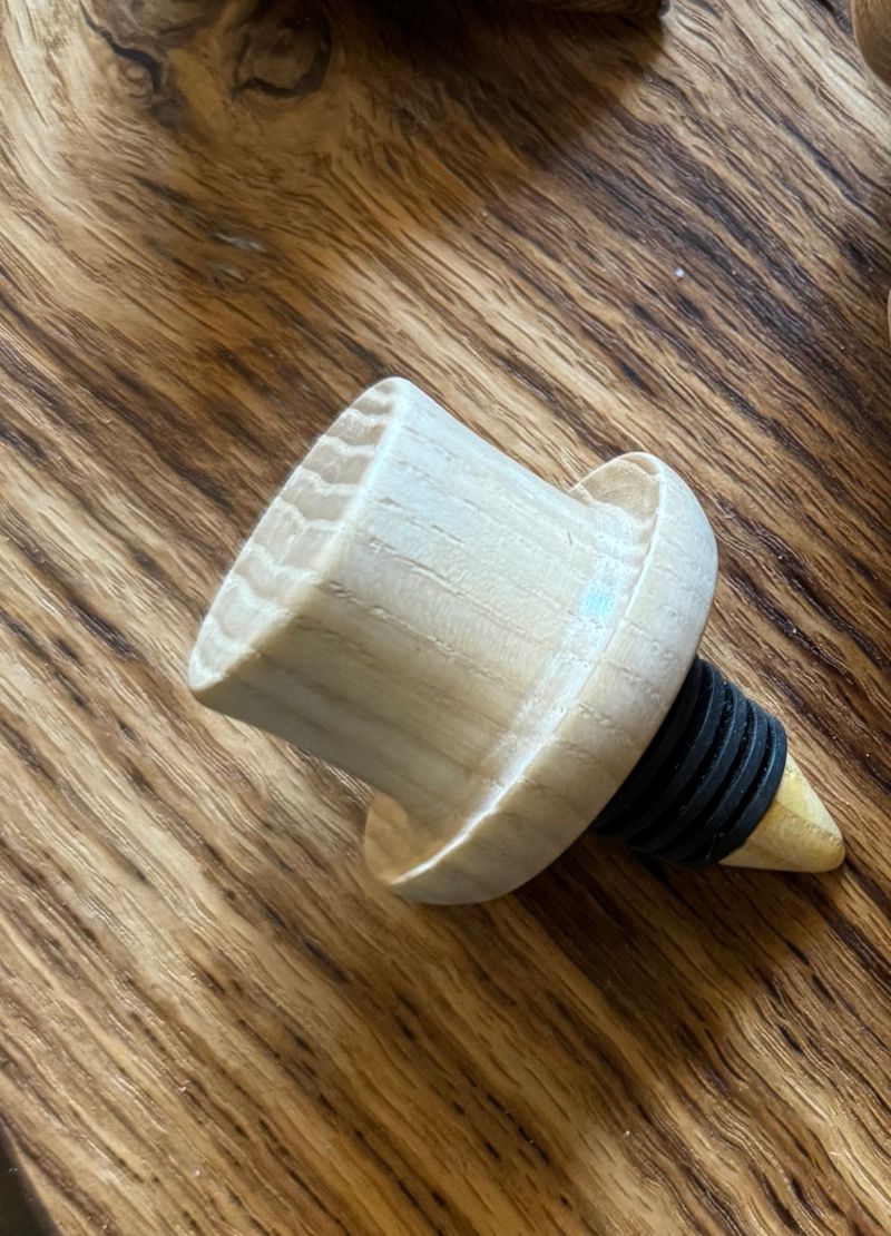 Wooden bottle stopper with a black rubber gasket on a wooden surface