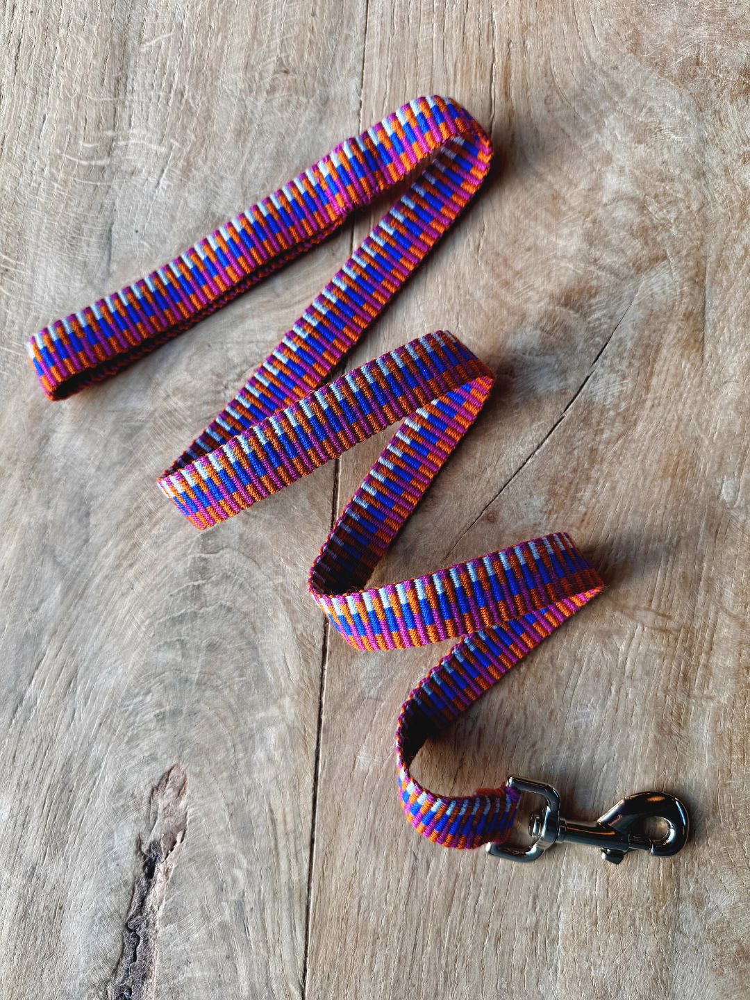 Brightly coloured handwoven dog lead on wooden surface