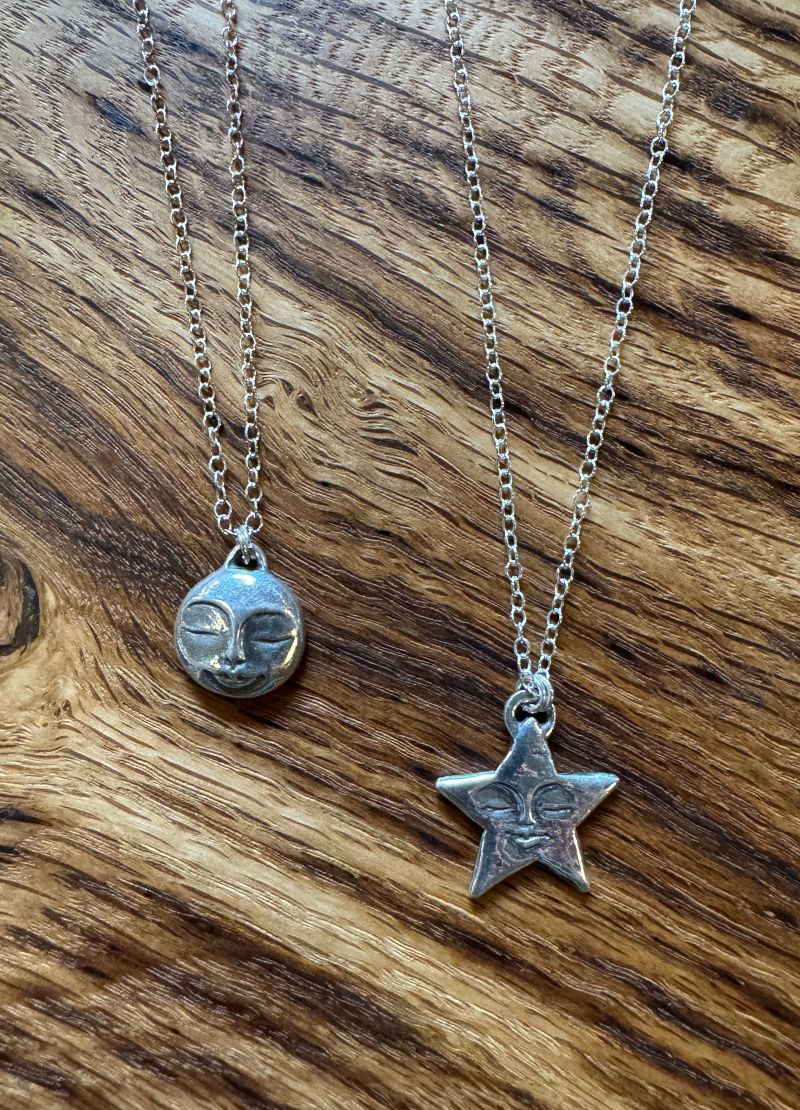 Two silver necklaces with pendants on a wooden surface