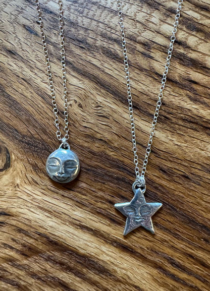 Two silver necklaces with pendants on a wooden surface