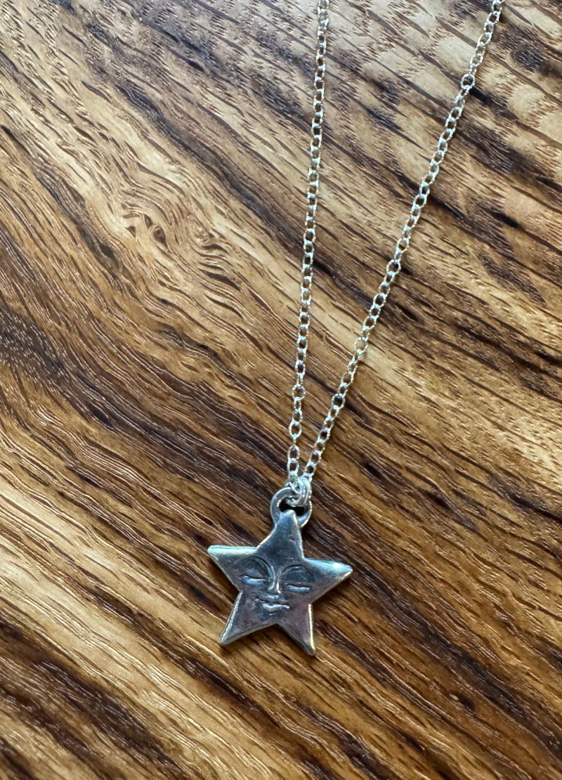 Silver star-shaped pendant necklace on a wooden surface