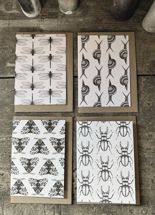 Four greeting cards with insect patterns on a wooden surface