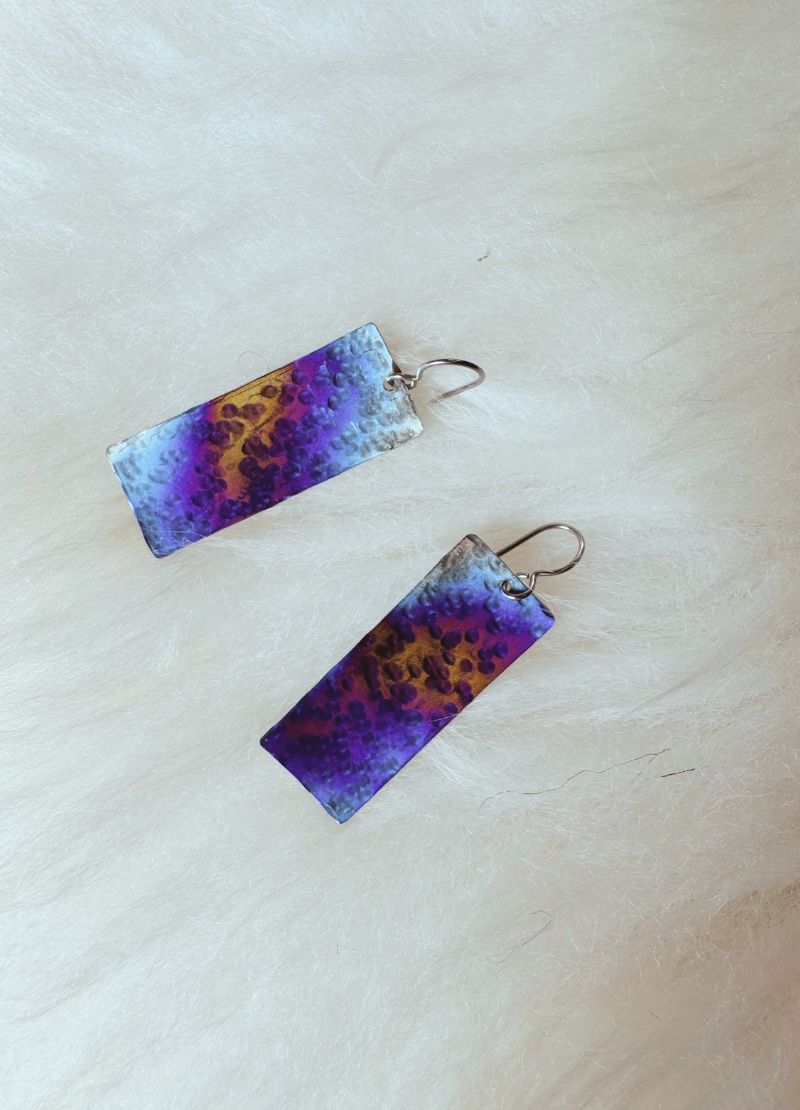 Pair of earrings with purple and blue gradient design on a light background