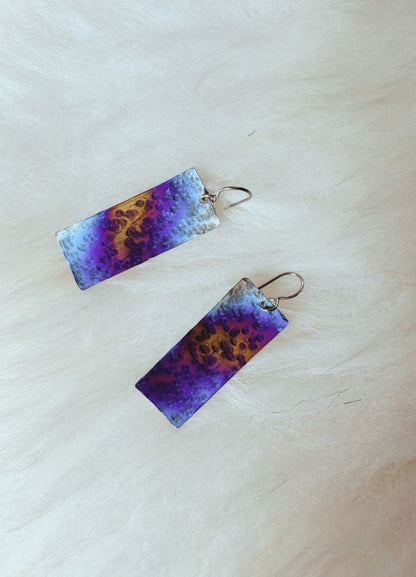 Pair of earrings with purple and blue gradient design on a light background